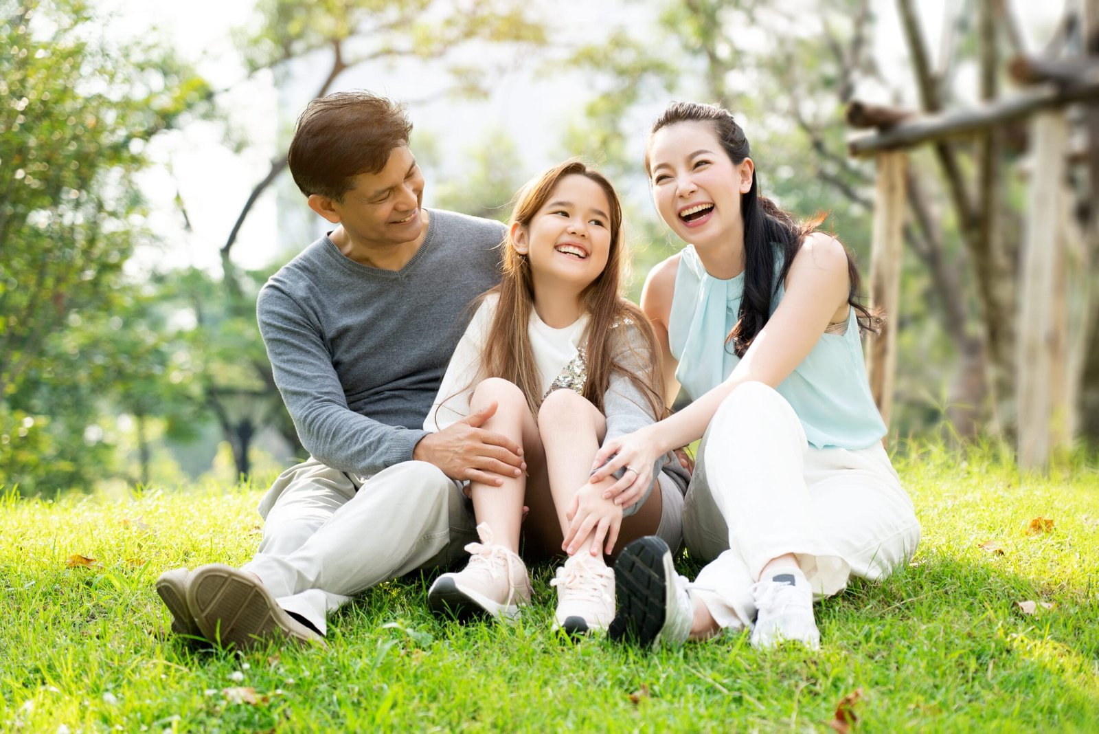 a family of 3 hanging out in a green park